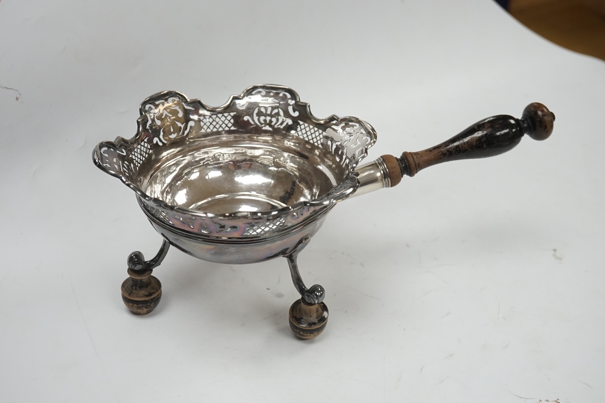 An early 19th century Dutch white metal bowl, with pierced border and turned wooden handle, length 27cm, (a.f.), together with a pair of continental white metal mounted wine coasters, diameter 12.7cm. Condition - poor to